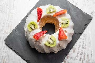 A gugelhupf (kuglof) with fruits on a black plate