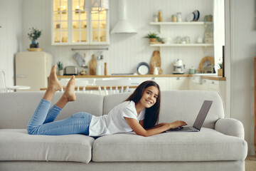 Cute preteen 12s girl use laptop lying on couch
