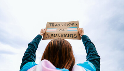 Transgender woman fighting for trans human rights at gay pride protest holding banner - People...