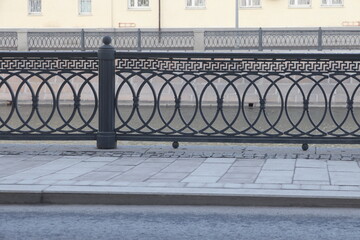 Image of a decorative wrought iron fence made of cast iron and curb stone. Metal fence close-up. Minimalism.