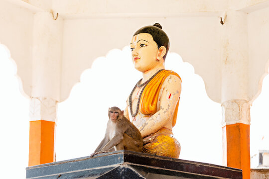 The monkey is sitting near the statue. Chitrakoot. India