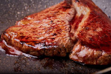 Cooked beef steak resting in a pan.