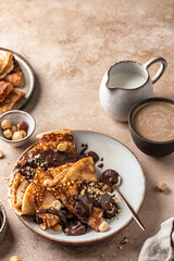 Crepes with chocolate and hazelnuts on beige background. Thin pancakes as delisious breakfast or dessert concept, Pancake day, Maslenitsa. Copy space