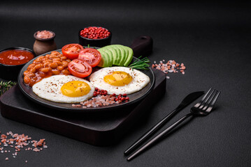 Delicious nutritious English breakfast with fried eggs, tomatoes and avocado