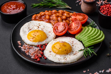 Delicious nutritious English breakfast with fried eggs, tomatoes and avocado