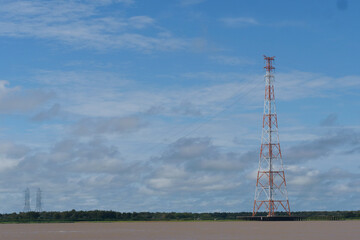 A row of red and white electricity transmission towers over the Amazon river in Brazil