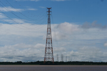 A row of red and white electricity transmission towers over the Amazon river in Brazil