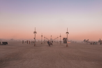 People walking towards sunset at a festival in the desert. Beautiful music festival in a desert at...