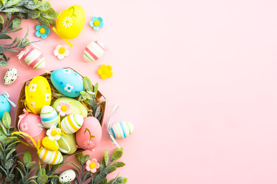 Easter eggs in the nest on pink background. Easter decor. Flat lay image with copy space.