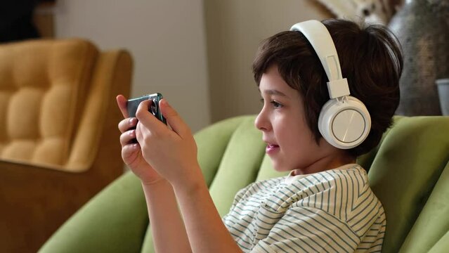 young boy sits comfortably on a couch, deeply engrossed in his phone.child fully immersed in the digital world before him.