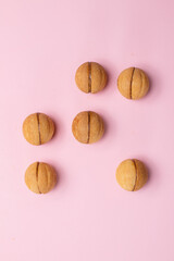 Walnut-shaped cookies with boiled condensed milk on a pale pink background. Mocap.
