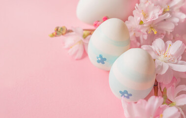 Close up of easter eggs and cherry flowers on a pink background with bokeh and copy space. Minimal concept