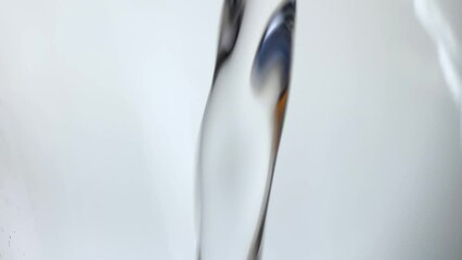 Water stream in slow motion falls on smooth clean surface, creating air bubbles, drop splashes after falling. Freshness of a clear blue liquid poured into transparent container on white background - Powered by Adobe