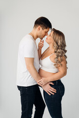 a couple waiting for a child in white T-shirts and jeans on a white background.