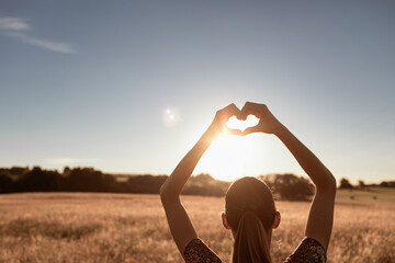 Female holding up heart to the sunset . I love nature concept.	