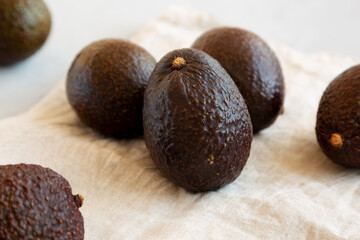 Raw Organic Hass Avocados on a gray background, side view.