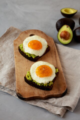 Homemade Avocado Toast with Eggs on a rustic wooden board, side view.