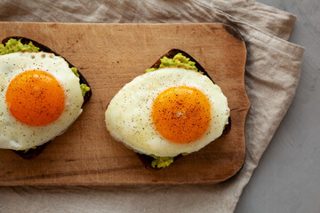 Homemade Avocado Toast with Eggs on a rustic wooden board, top view. Flat lay, overhead, from above.