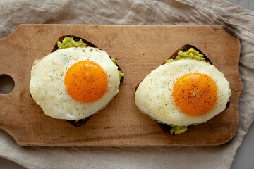 Homemade Avocado Toast with Eggs on a rustic wooden board, top view. Flat lay, overhead, from above.