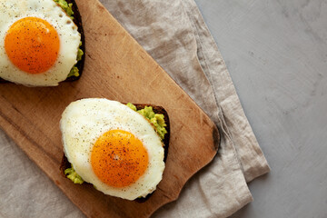 Homemade Avocado Toast with Eggs on a rustic wooden board, top view. Flat lay, overhead, from above. Copy space.