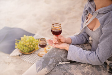A girl drinks wine from a glass at a picnic outdoors at the sea. Joint trip to the sea. Romantic date.

