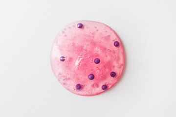 Round drop of pink gel scrub with bubbles on white background. Concept of skin care and exfoliation. Backdrop for skincare product. Selective focus