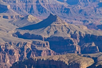 Bright desert sunlight shines down on the Grand Canyon, casting shadows on every crease and layer...