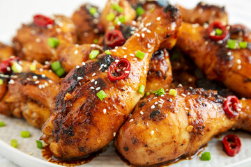 Homemade Easy Sticky Chicken Drumsticks on a Plate on a white wooden background, side view. Close-up.