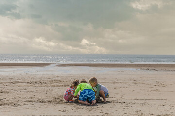 Three small children playing in the sand on an ocean-front beach