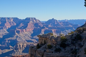 Bright desert sunlight shines down on the Grand Canyon, casting shadows on every crease and layer of the eroded canyon carved over many years by the Colorado River thousands of feet below