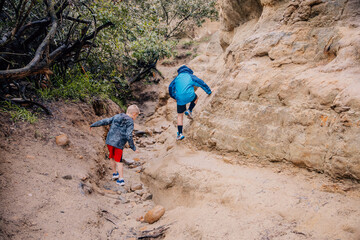 Boys hiking climbing through a sandstone slot canyon