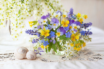 A bouquet of spring blue, yellow, white, violet flowers in a vase on the table. Pansies, forget me...