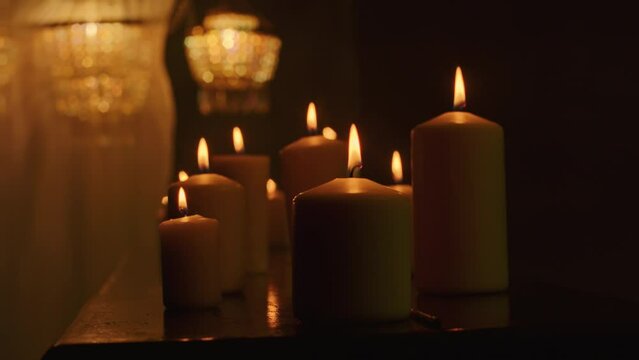 Black candles cast an eerie glow on the dark background as a witch performs a magic ritual with voodoo and paganism. A close-up reveals the intensity of the mystic rite
