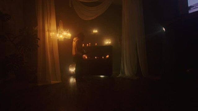 The witch summons ancient powers with black candles in a dark background, performing a mystic rite with voodoo and paganism. The close-up captures the magic and mysticism of the ritual