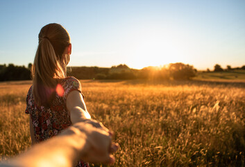 woman walking in the meadow field holding man's hand 