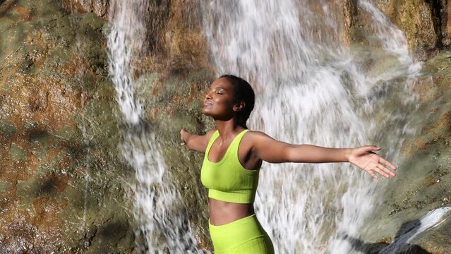 Calm And Smiling Black Female Opening Arms And Breathing With Closed Eyes. Relax woman in nature