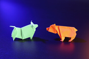 Origami bull and bear trading on dark background in neon light with copy space