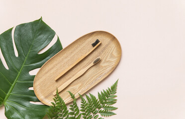 Bamboo toothbrush on a table with copy space on a pink background. Styled composition of flat lay...