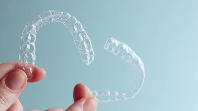 Aligners for aligning teeth on a blue background in a female hand