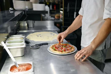 Wandcirkels plexiglas Pizzaiolo making pizza at kitchen with closeup focus on hand © Nomad_Soul