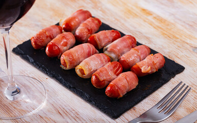 Sausage rolled with bacon on black dish. High quality photo