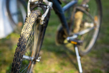 Dirty bike wheel. Bicycle rides, travel, outdoor activities. The bike is on the green grass.