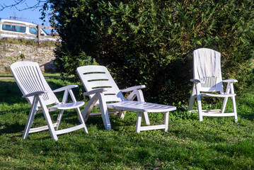 Empty sun loungers on grass in courtyard of house. Places to relax near green tree. Relaxation.
