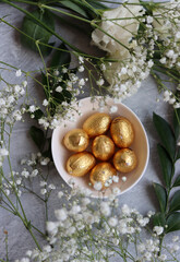 Foil wrapped Easter chocolate eggs in a glass bowl. Easter celebration concept. Colorful still life with sweets. Textured background with copy space. Easter greeting card. 