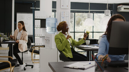 African american girl using smartphone for videocall, attending corporate meeting with people on online conference. Young employee talking to coworkers on videoconference with phone.