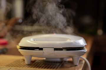 Obraz premium The sandwich maker is smoking. Steam comes out when making sandwiches.