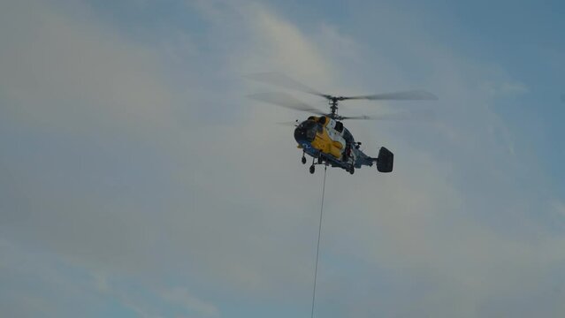 Helicopter with rope flies. Coaxial helicopter carries cargo