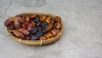 Set of various dates in bamboo basket over cement texture background. selective focus