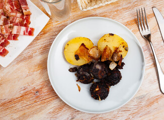 Blood sausage black pudding served with boiled potato and fried onion