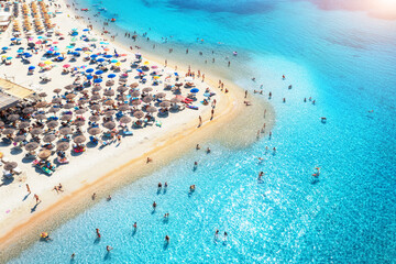 Aerial view of colorful umbrellas on beach, people in blue sea